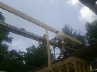Carpenter setting a ridge beam over a new addition frame — Ice Dam Removal by Roofing Brothers in Eight Mile