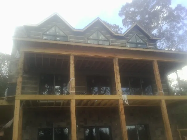 Dormers and porch framing on a large log home under construction — Roof Coating work by our crew in Eight Mile