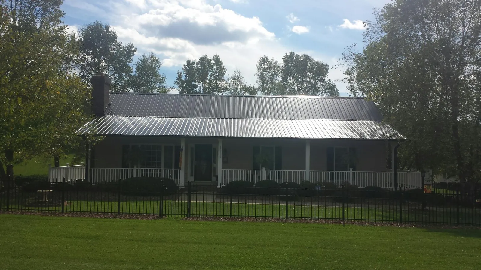 Gray metal roof on a brick ranch with a full width front porch — Gutter Guard Installation work by our crew in Eight Mile
