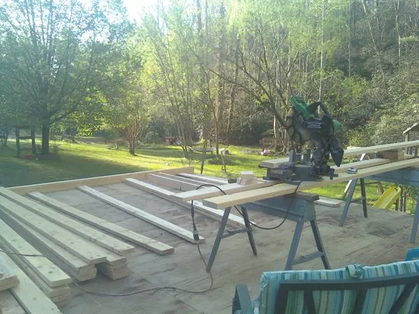 Miter saw and framing lumber on a deck under construction in Eight Mile