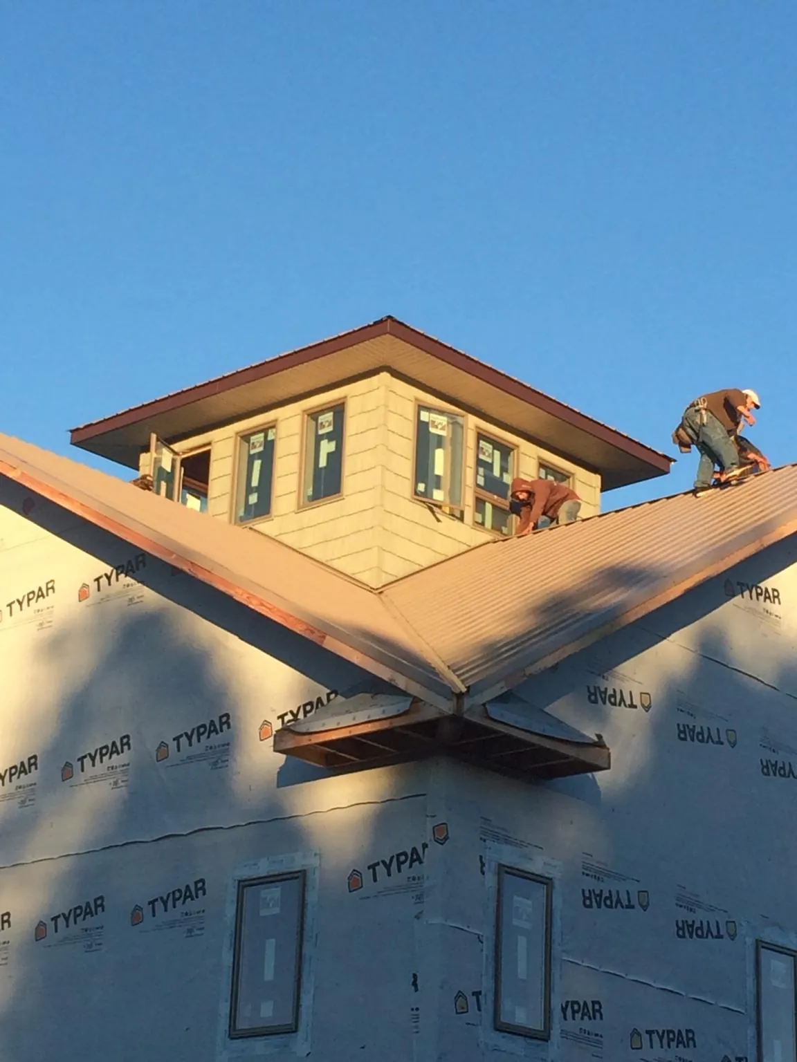 Roofers working around a rooftop cupola on a new metal roof at sunset — Roof Waterproofing in Eight Mile by Roofing Brothers